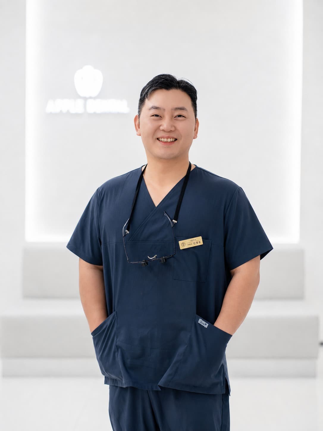 안광성 대표원장. 네이비 스크럽을 입고 정면을 보고 서 있다